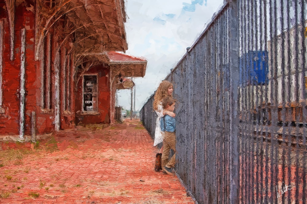 Two children looking through a fence waiting for a train